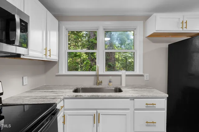 a kitchen with granite countertop a sink stove and cabinets