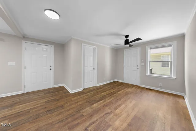 a view of empty room with wooden floor and fan