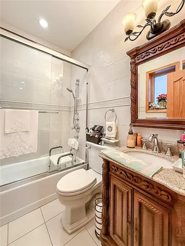 a bathroom with a granite countertop sink a toilet a mirror and bathtub
