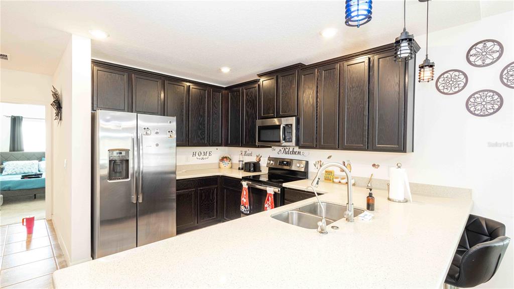 815 Montgomery Drive Davenport, FL 33897 - Photo 5 of 24 a kitchen with stainless steel appliances a sink a stove a refrigerator and cabinets