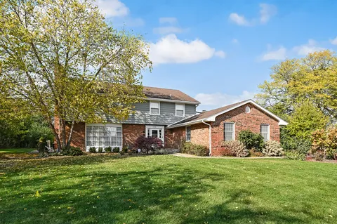 a front view of a house with a garden and trees
