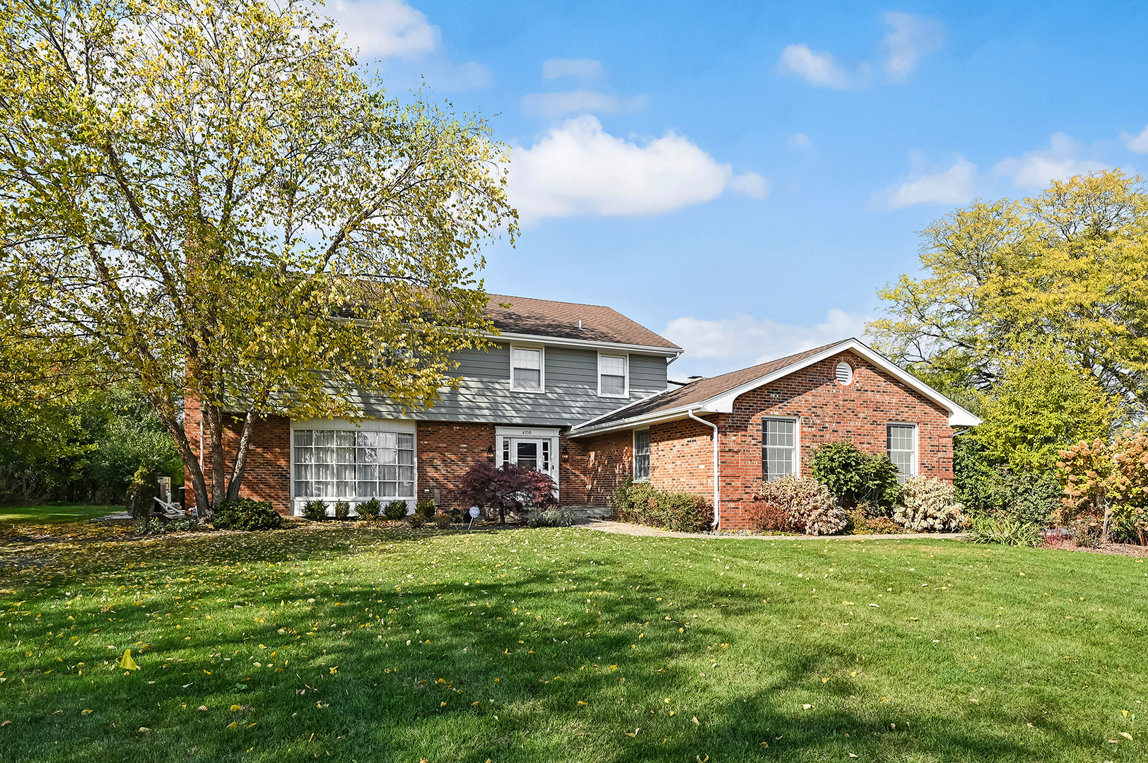 a front view of a house with a garden and trees