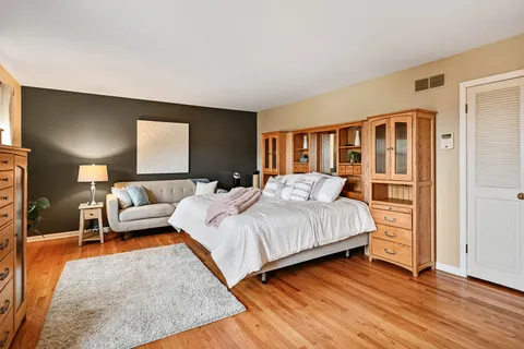 a bedroom with a bed wooden floor and lamp