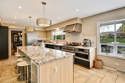 a kitchen with stainless steel appliances granite countertop a stove and a view of living room