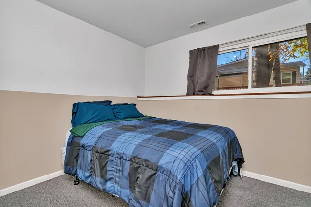 a bedroom with a bed a window and painting on the wall