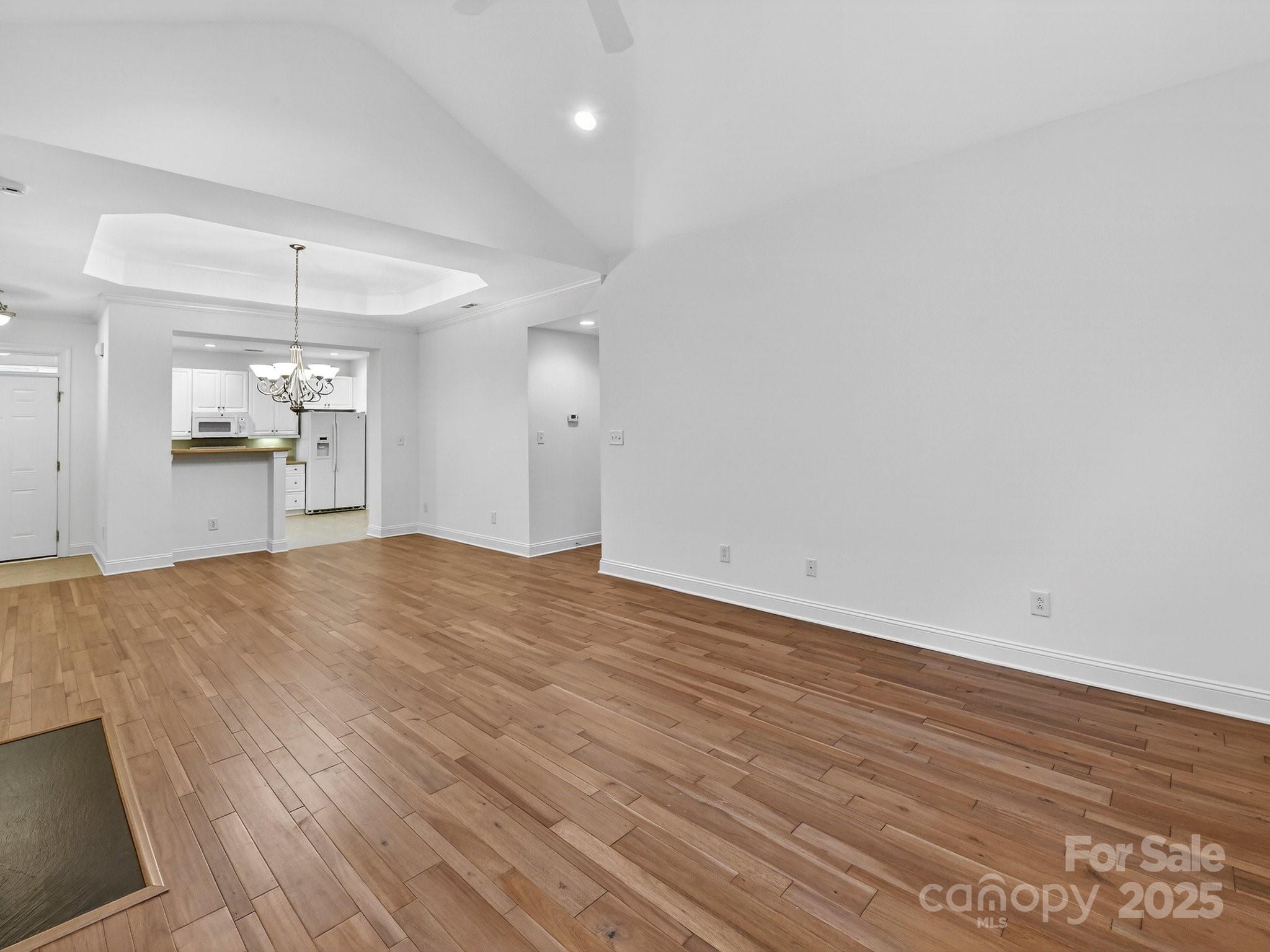 2963 Bellasera Way Matthews, NC 28105 - Photo 11 of 46 an empty room with wooden floor and kitchen view