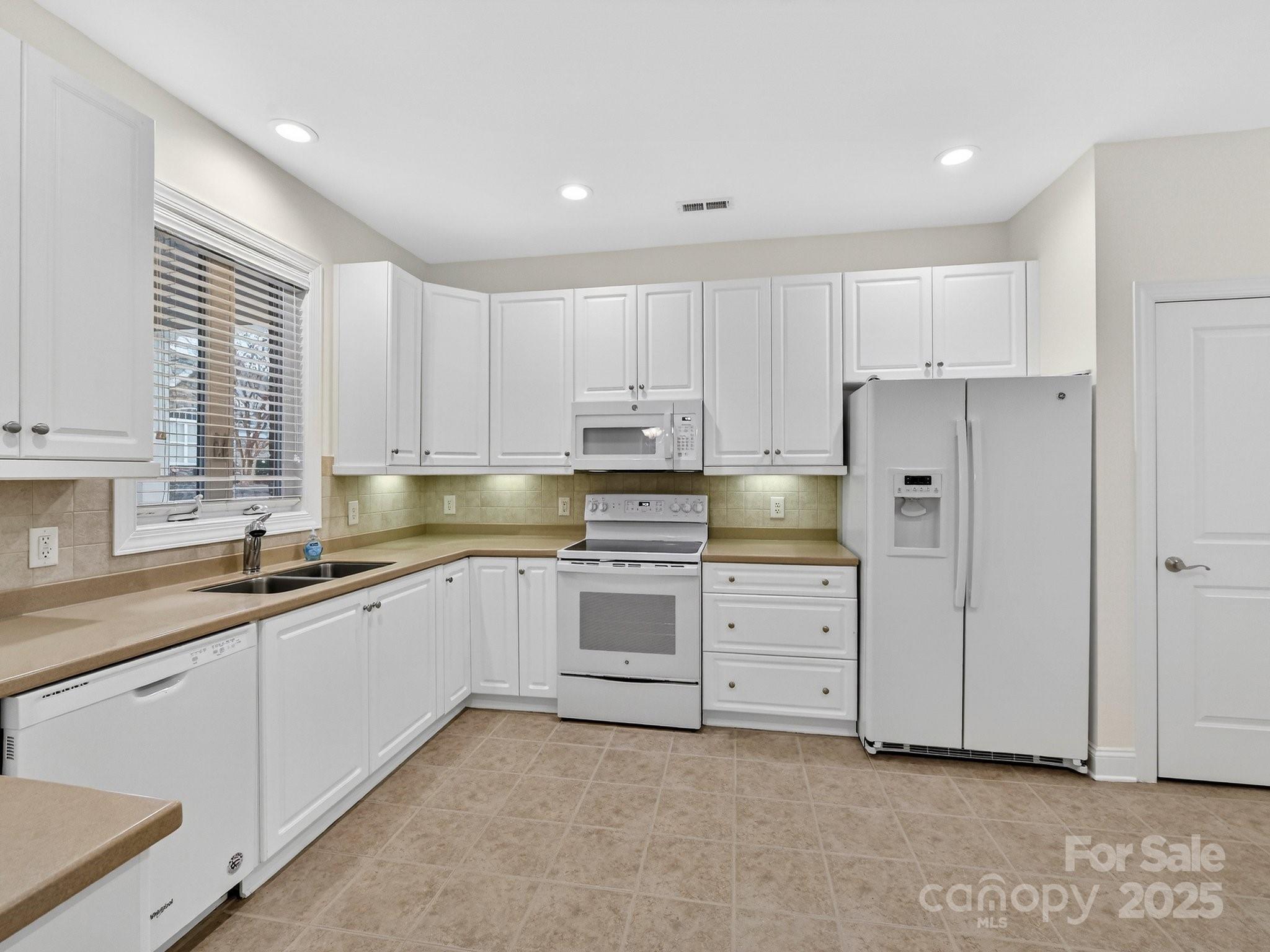 2963 Bellasera Way Matthews, NC 28105 - Photo 14 of 46 a kitchen with granite countertop white cabinets and white stainless steel appliances