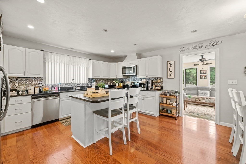 28 Gammons Road Acushnet, MA 02743 - Photo 17 of 39 a kitchen with stainless steel appliances granite countertop a stove top oven a sink a dining table and chairs with wooden floor