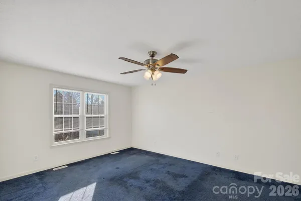 an empty room with window and ceiling fan
