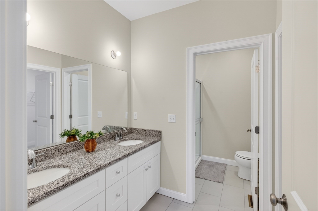 10 Logans Run, Unit 10 Millbury, MA 01527 - Photo 24 of 42 a bathroom with a granite countertop sink a toilet and a mirror