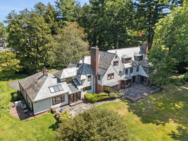 an aerial view of a house with swimming pool and large trees
