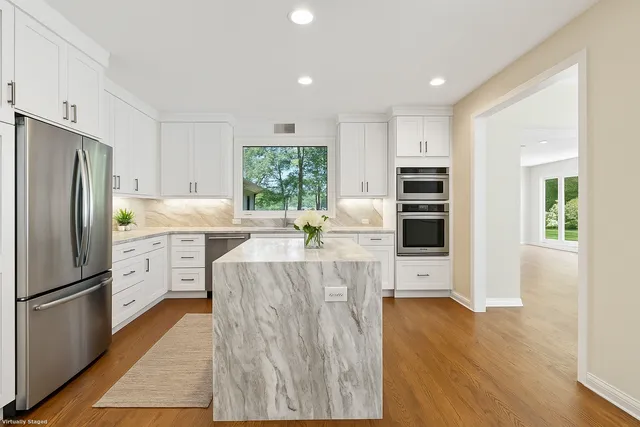 a kitchen with stainless steel appliances a refrigerator a stove a sink cabinets and a dining table