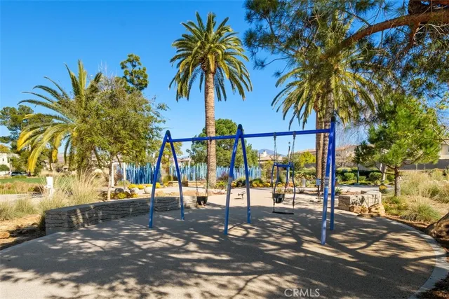 a view of swimming pool with a lawn chairs and palm trees