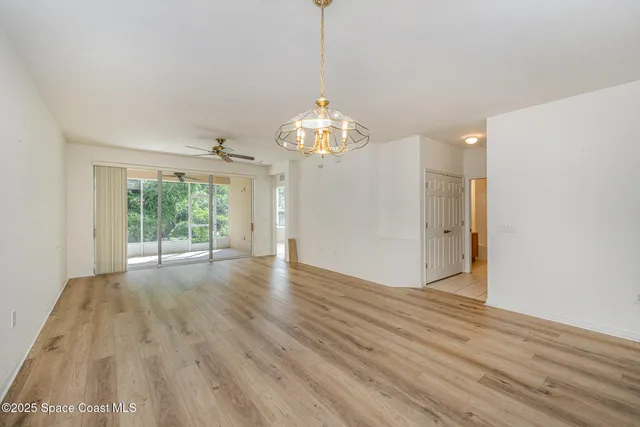 a view of a room with wooden floor chandelier and windows