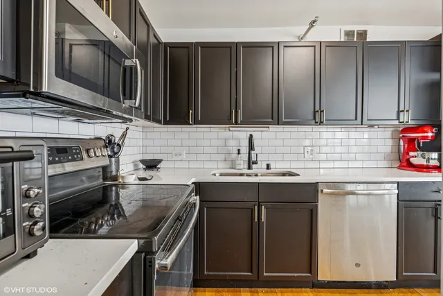 a kitchen with a refrigerator a stove and a dining table with wooden floor