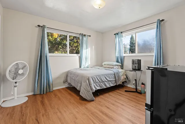 a bedroom with a bed a mirror on dresser and a window