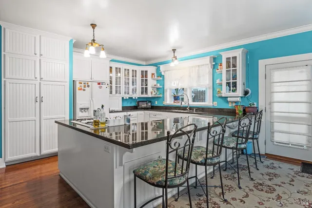 a kitchen with stainless steel appliances granite countertop a table chairs sink and cabinets