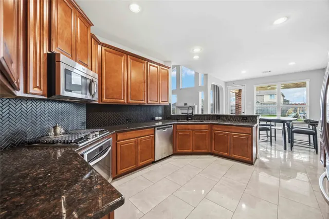 a kitchen with stainless steel appliances granite countertop a stove a sink and a microwave