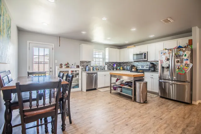 a kitchen with a dining table chairs refrigerator and cabinets