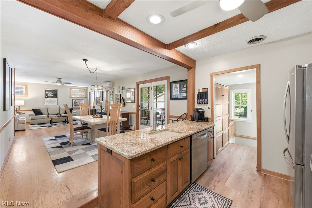 233 Sunset Road Avon Lake, OH 44012 - Photo 13 of 50 Kitchen island featuring a granite countertop and integrated sink, stainless steel dishwasher, and wood cabinetry