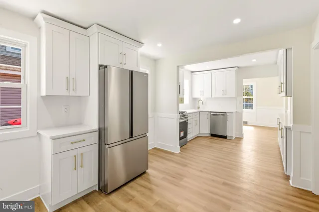 a kitchen with a refrigerator a stove top oven and white cabinets