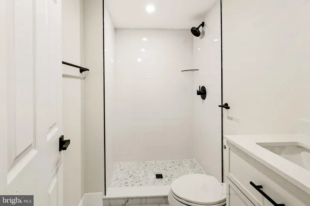 a bathroom with a granite countertop bathtub shower sink vanity and toilet