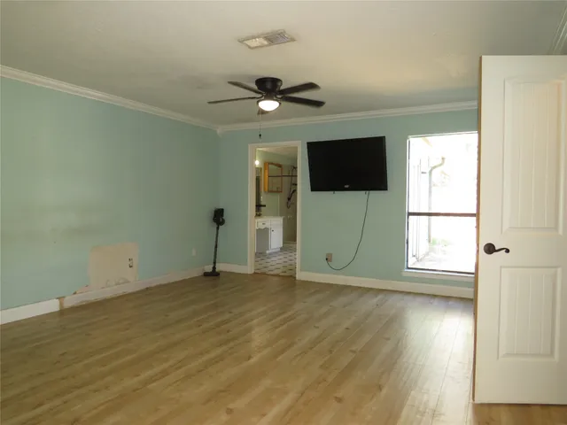 a view of empty room with wooden floor and fan