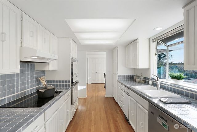 a kitchen with granite countertop a sink a counter space appliances and cabinets