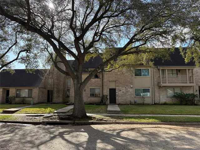 a view of a house with a yard and large tree