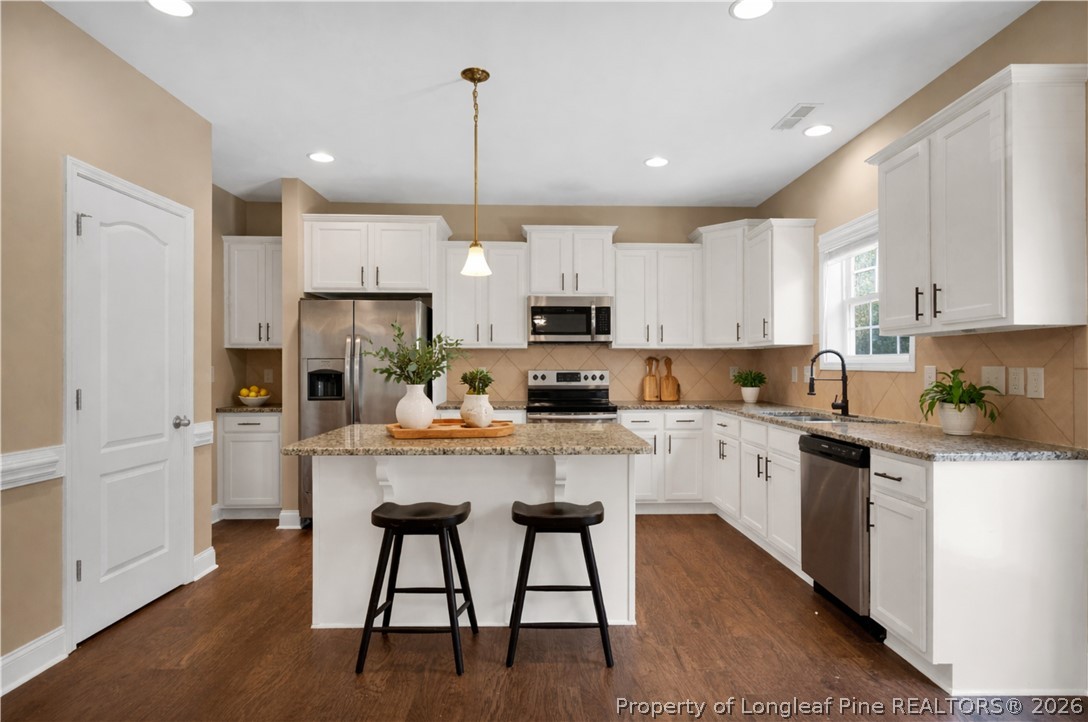 448 Pittfield Run Cameron, NC 28326 - Photo 5 of 43 a kitchen with stainless steel appliances granite countertop white cabinets a sink a stove a dining table and chairs