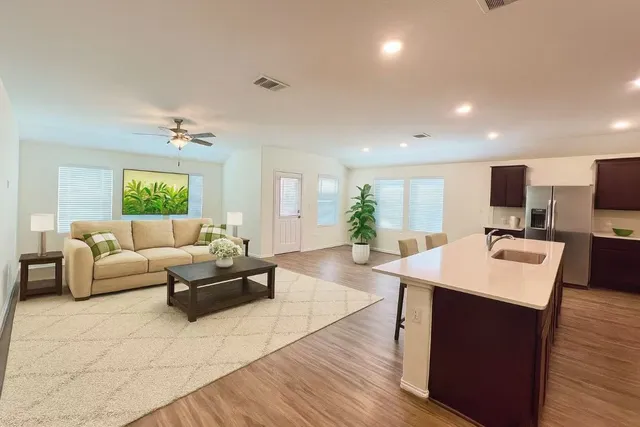 a living room with furniture kitchen view and a wooden floor