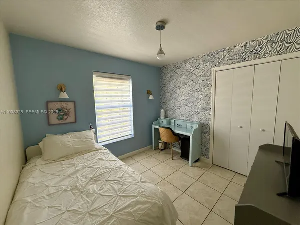 a bedroom with a bed and a flat tv screen on the dresser