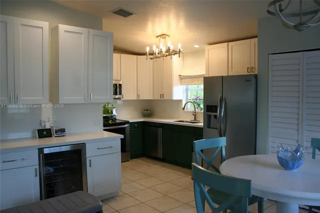 a kitchen with stainless steel appliances a refrigerator sink stove dining table and chairs