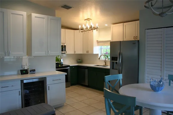 a kitchen with stainless steel appliances a refrigerator sink stove dining table and chairs