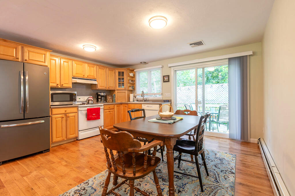 17 Valley Road Mashpee, MA 02649 - Photo 7 of 19 a kitchen with stainless steel appliances granite countertop a stove a refrigerator a sink a dining table and chairs with wooden floor