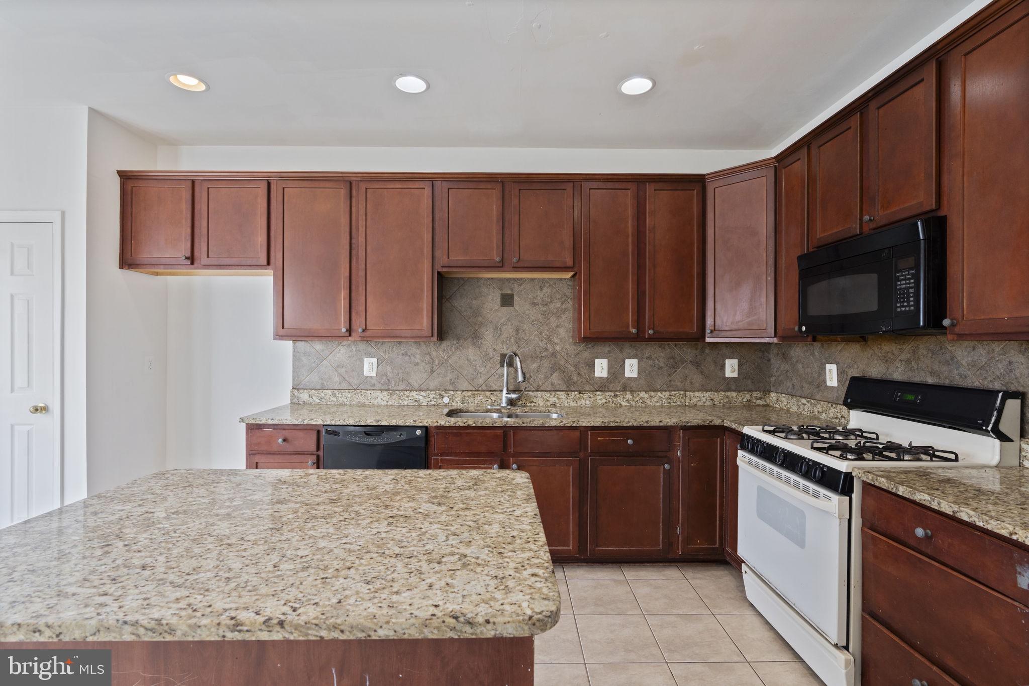 811 Middle River Road Baltimore, MD 21220 - Photo 14 of 55 a kitchen with stainless steel appliances granite countertop wooden cabinets a stove top oven a sink and dishwasher