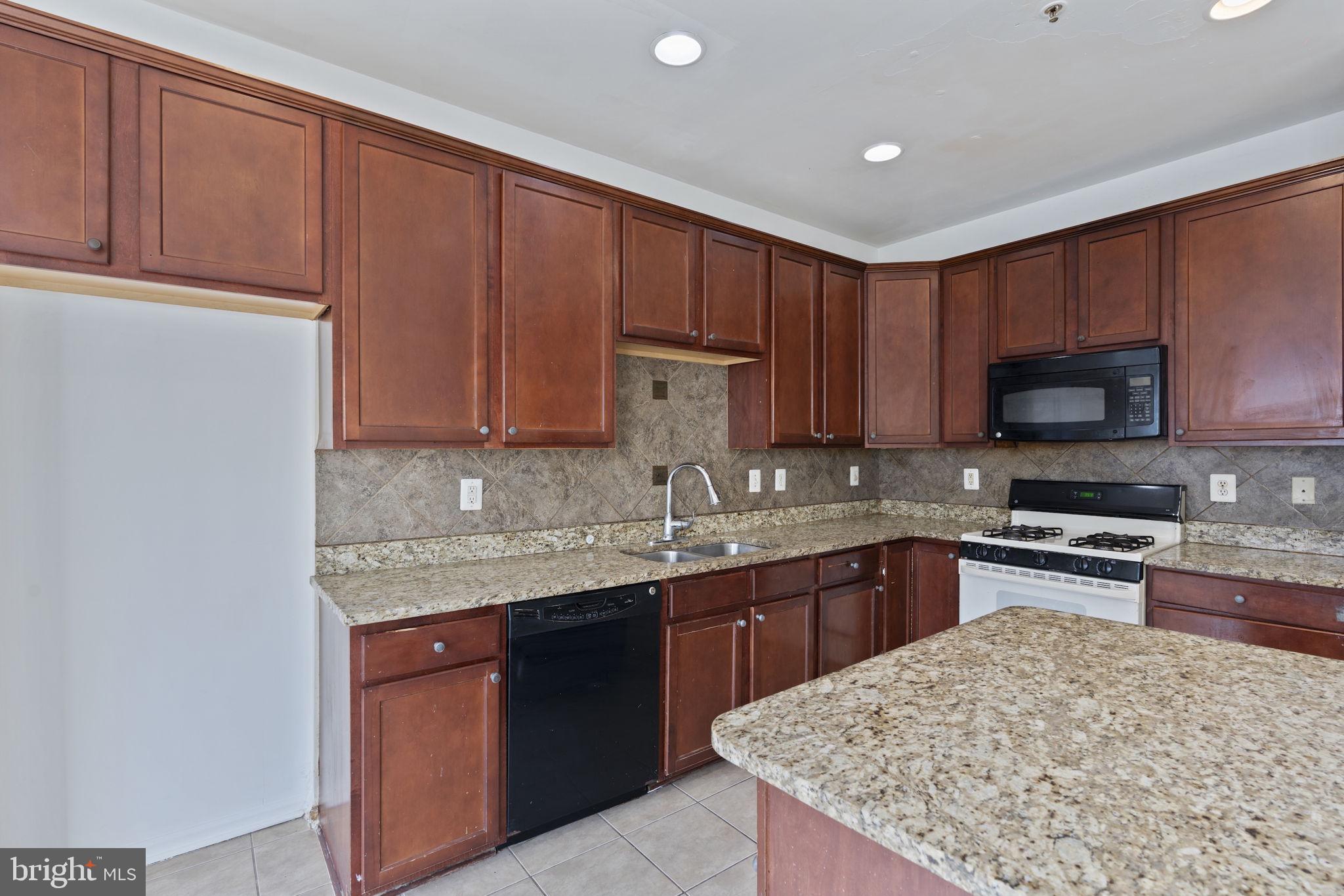 811 Middle River Road Baltimore, MD 21220 - Photo 15 of 55 a kitchen with granite countertop wooden cabinets a sink and dishwasher