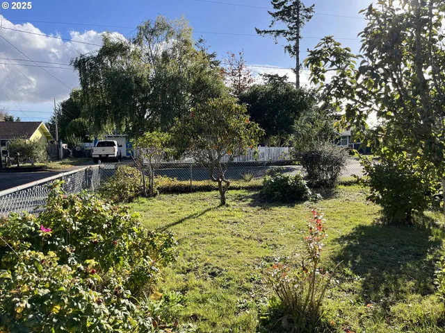 a backyard of a house with large trees and plants