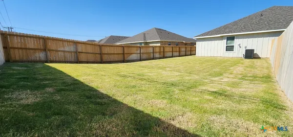 a view of a white house next to a yard with wooden fence