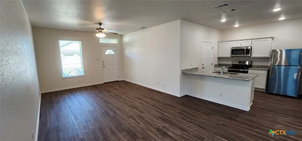 a view of kitchen with stainless steel appliances refrigerator stove microwave and cabinets