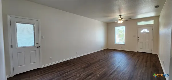 an empty room with wooden floor and windows