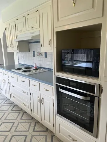 a kitchen with granite countertop white cabinets and appliances