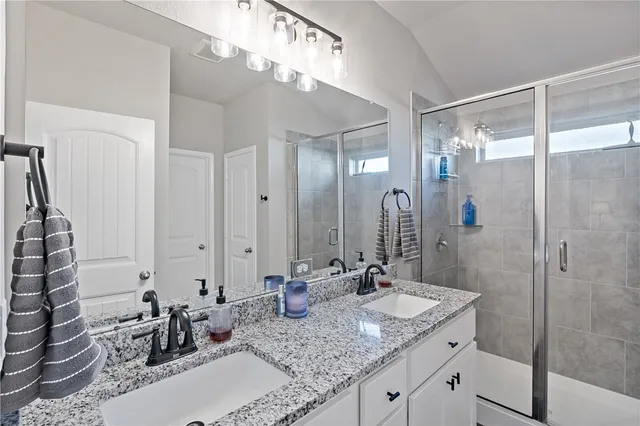 a bathroom with a granite countertop sink a mirror and shower