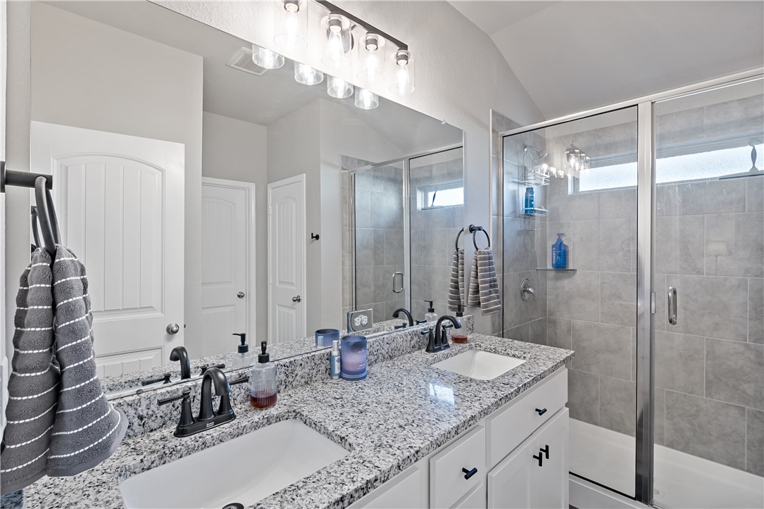 2135 Chief Street Bryan, TX 77807 - Photo 16 of 26 a bathroom with a granite countertop sink a mirror and shower