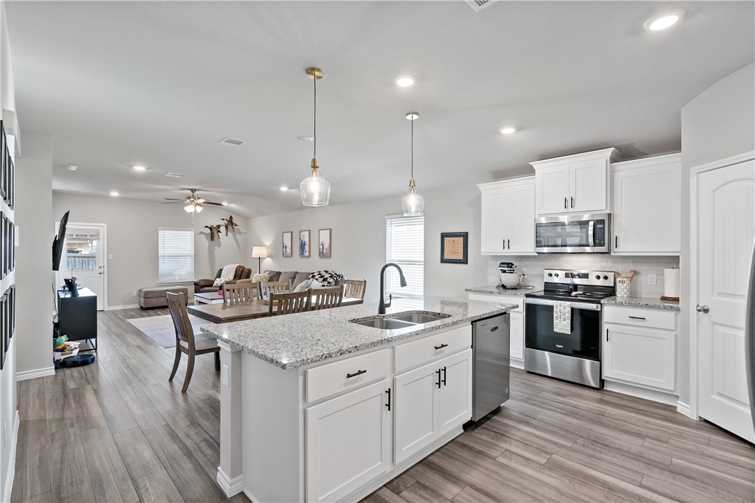 2135 Chief Street Bryan, TX 77807 - Photo 5 of 26 a kitchen with stainless steel appliances granite countertop a sink stove and wooden floor