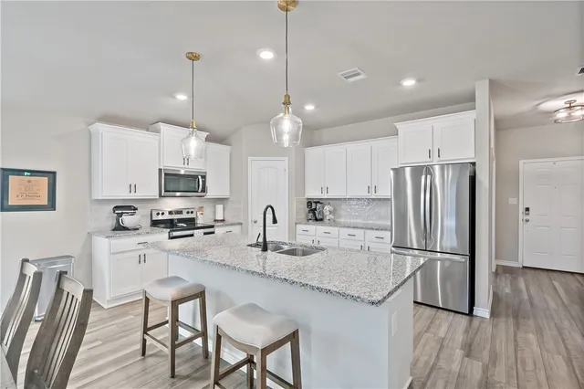 a kitchen with stainless steel appliances granite countertop a refrigerator a stove a sink a center island a table and chairs