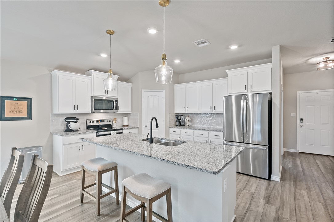 2135 Chief Street Bryan, TX 77807 - Photo 6 of 26 a kitchen with stainless steel appliances granite countertop a refrigerator a stove a sink a center island a table and chairs