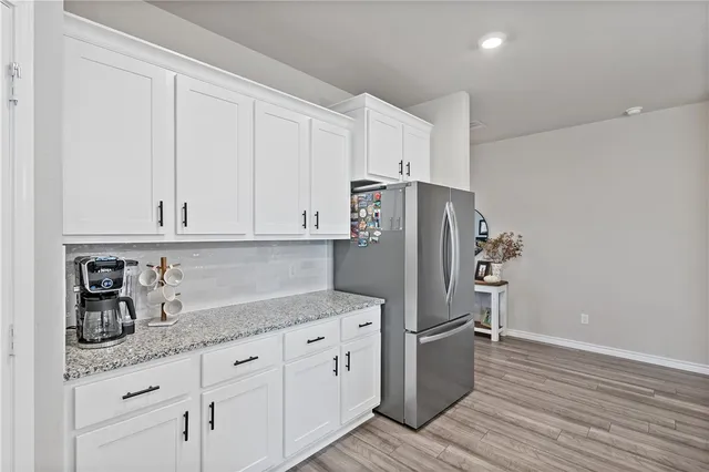 a kitchen with granite countertop white cabinets and refrigerator