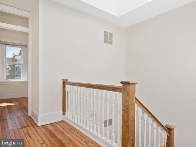 a view of a hallway with wooden floor and a bathroom