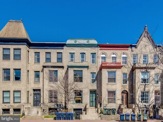 a front view of a building with lot of cars and trees